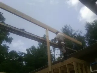 Carpenter setting a ridge beam over a new addition frame — Ice Dam Removal by Roofing Brothers in Centreville
